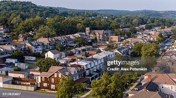 row houses and a church surrounded by tree area in palmerton, pa during the summer. holy trinity lutheran church towers the cityscape - carbon county pennsylvania stock pictures, royalty-free photos & images