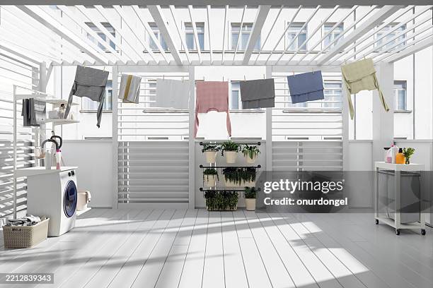 balkon mit waschmaschine, wäschekorb, topfpflanzen und hängender nasser kleidung - wäscheständer stock-fotos und bilder