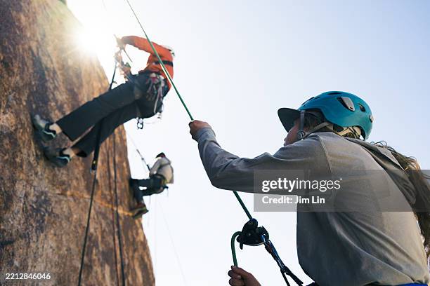 climbing student ascends with rope support from teammate below - sport climber stock pictures, royalty-free photos & images
