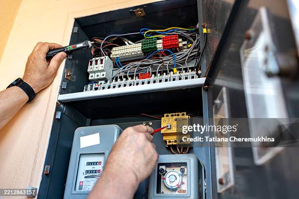 hands of electrician working on residential electrical panel with testing equipment - fuse box stock pictures, royalty-free photos & images