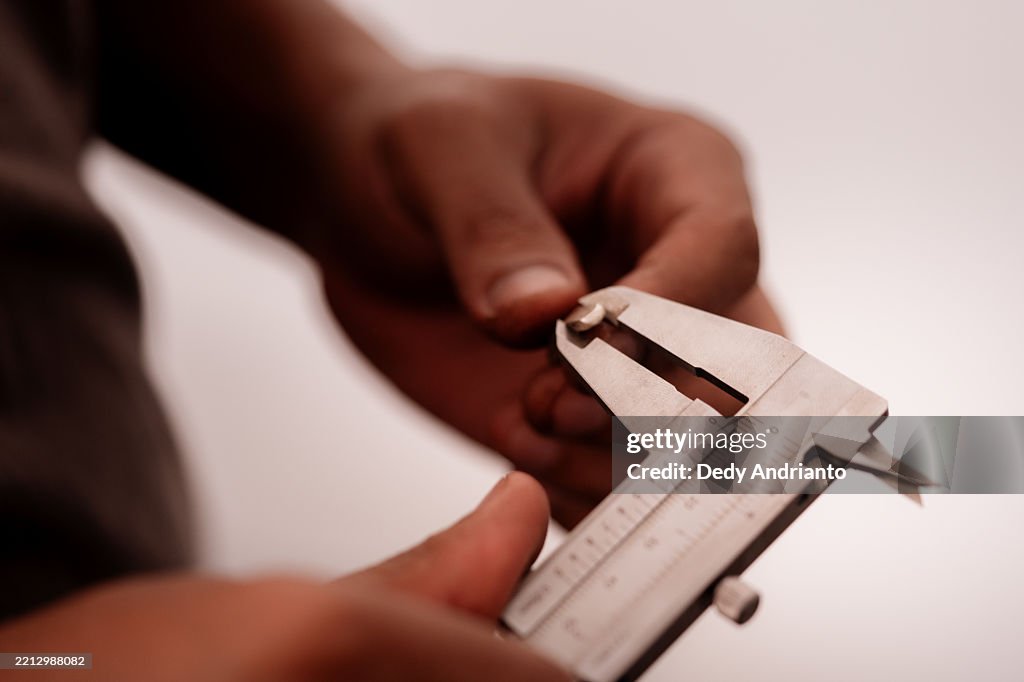 Close-Up of Artisan Measuring Jewelry White Gold Ingot with Caliper