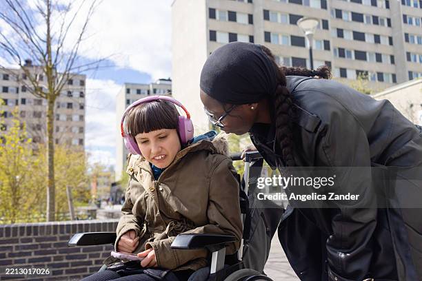 asistente de cuidado personal hablando con una adolescente en silla de ruedas al aire libre - discapacidad del desarrollo fotografías e imágenes de stock