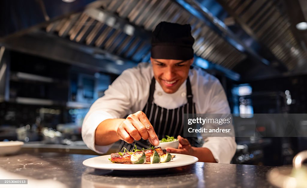 Chef decorating a plate while cooking in a commercial kitchen