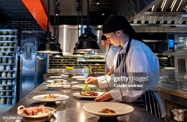koch, der in einem restaurant arbeitet und teller auf der küchentheke dekoriert - gewerbliche küche stock-fotos und bilder