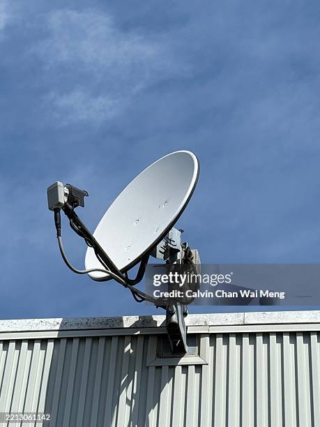 satellite dish mounted on a metal rooftop structure with blue sky in japan - satellite dish home stock pictures, royalty-free photos & images