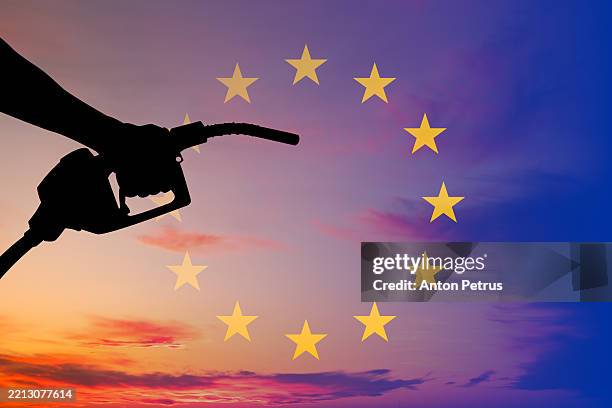 hand holding fuel nozzle with the eu flag in the background - benzintank stock-fotos und bilder