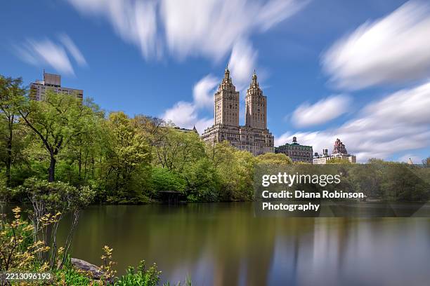 long exposure of clouds over the san remo apartment buildings along central park west as seen from the lake in central park, manhattan - san remo apartments nyc stock pictures, royalty-free photos & images