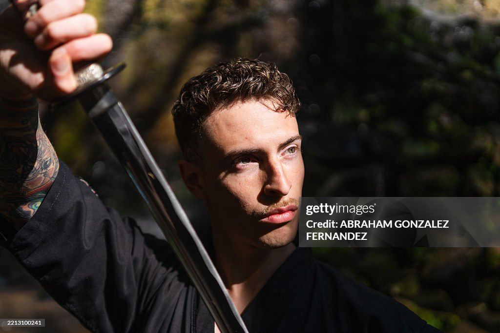 Artiste martial pratiquant le kata avec le katana au milieu d’un paysage naturel, affichant un mouvement concentré et une discipline guerrière traditionnelle