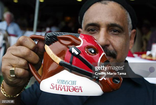 Diego Paler holds his collectible Seabiscuit mug at Saratoga Race Course during opening weekend of the thoroughbred racing season July 27, 2003 in...