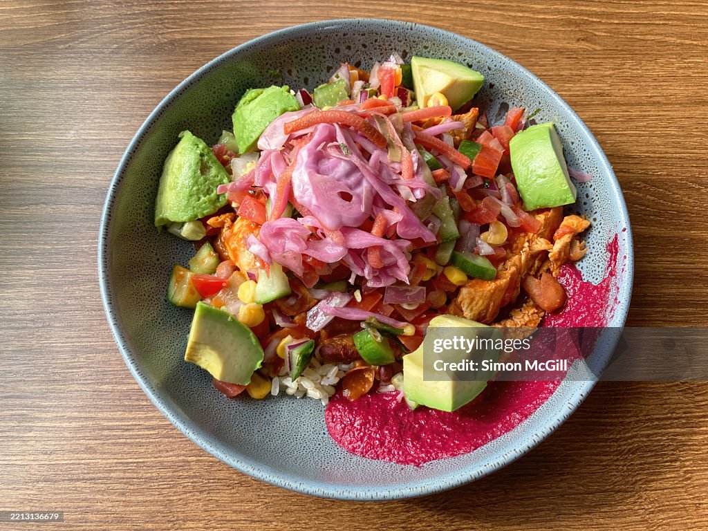 Burrito bowl with chicken, smokey beans, beetroot hummus, spinach, brown rice, salsa, pickled red onion, and avocado
