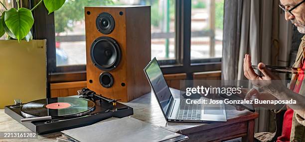 hombre usando tecnología moderna junto a tocadiscos y altavoces de estilo retro - equipo de alta fidelidad fotografías e imágenes de stock