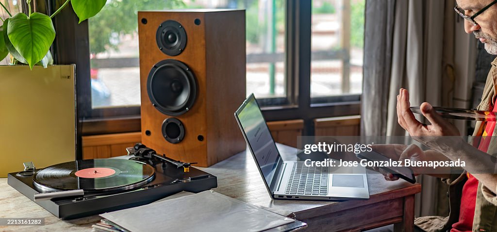 Man using modern technology next to retro style turntable and speakers