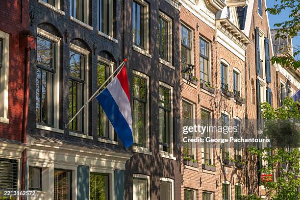 dutch flag on traditional amsterdam building - dutch flag stock pictures, royalty-free photos & images