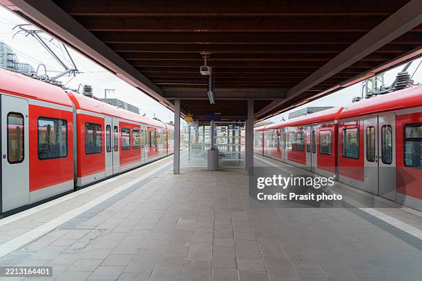 train platform with two red commuter trains - gare ferroviaire photos et images de collection
