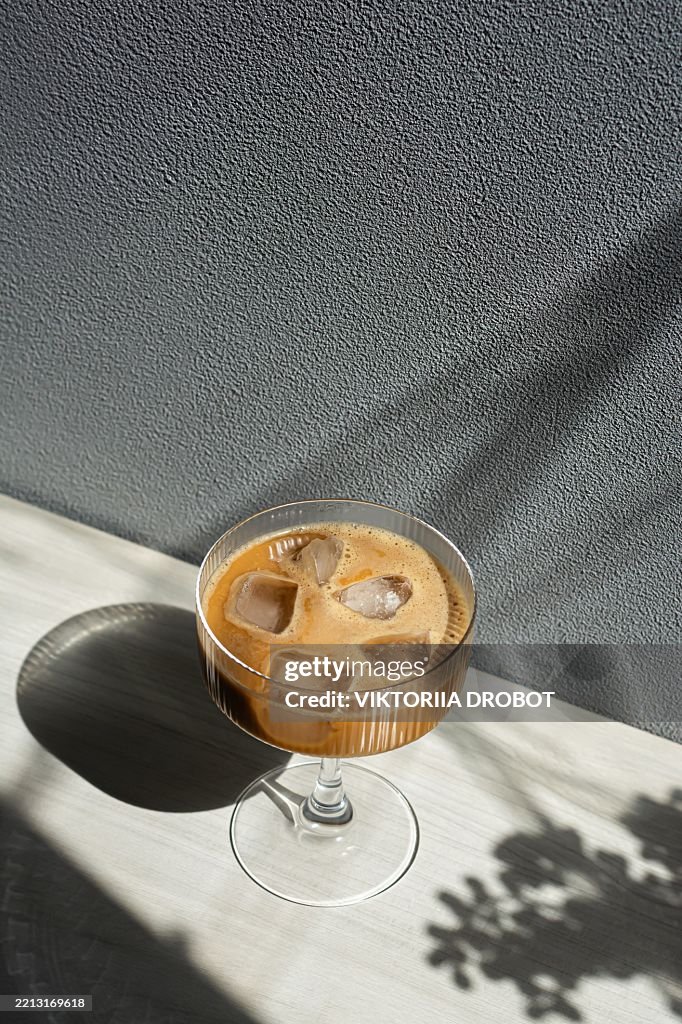 Coffee drink with ice in a glass on a gray background. The concept of alcoholic, non-alcoholic drinks, mocktail.