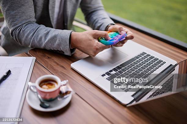 businessman playing with pop it toy while working on laptop - neurodiversity stock pictures, royalty-free photos & images