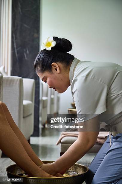 spa professional providing relaxing foot bath treatment in serene wellness setting - champa stock pictures, royalty-free photos & images
