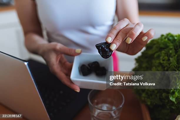 close-up of hands holding a dried plum in a kitchen setting - dried plum stock pictures, royalty-free photos & images