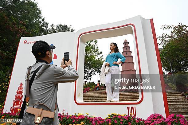 This photo taken on March 31, 2025 shows visitors posing for photos in front of the Hongta, or red pagoda, outside the Tobacco Cultural Center in...