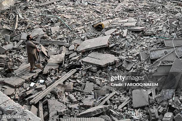 Locals stand on the debris of destroyed structures at the Government Health and Educational complex in Muridke about 30 kilometres from Lahore, on...
