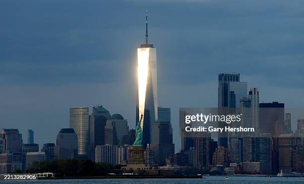 The sun sets on the skyline of lower Manhattan and One World Trade Center behind the Statue of Liberty in New York City on May 3 as seen from Jersey...