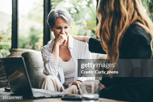 Two middle-aged women talk, expressing support and sympathy for each other. Two middle-aged women talk, expressing support and sympathy for each other.