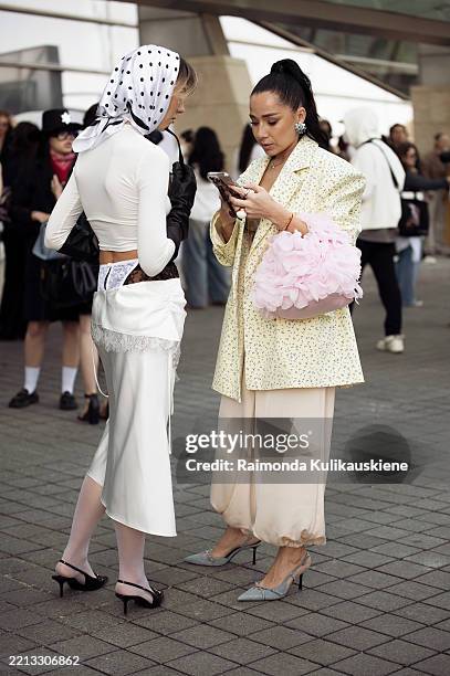 Alexandra Ishutina wears white silk skirt, white long sleeve top, white and black head scarf with black polka dots, black leather gloves, white...