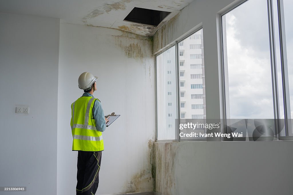 Asian Chinese female inspector hand touching the water leaking defect wall to check any moisture stock photo