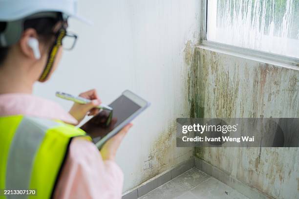 closeup asian chinese female construction inspector recording building defect list using smart tablet stock photo - luchtvochtigheid stockfoto's en -beelden