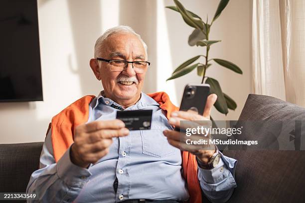 senior man using a smartphone while shopping online from home - financial literacy stock pictures, royalty-free photos & images