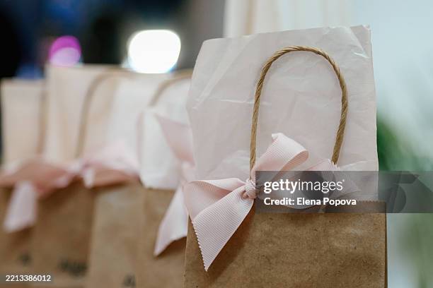 craft brown paper shopping bags with elegant pink ribbons for her in a row - geschenktüte einwickelpapier stock-fotos und bilder