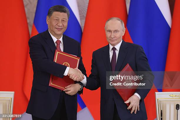 Russian President Vladimir Putin exchanges documents with Chinese President Xi Jinping during their meeting at the Grand Kremlin Palace, May 8, 2025...