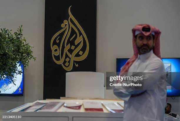 Visitors explore the booth of Al Jazeera TV Channel following the opening of the 34th edition of the Doha International Book Fair at the Doha...