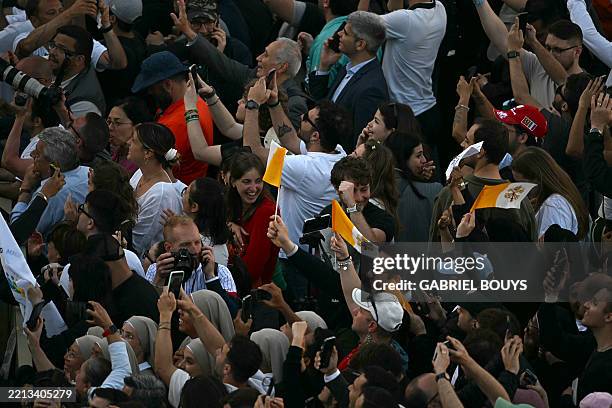 People react and wave Vatican flags as white smoke signals that cardinals elected a new pope during their conclave in the Vatican on May 8, 2025.