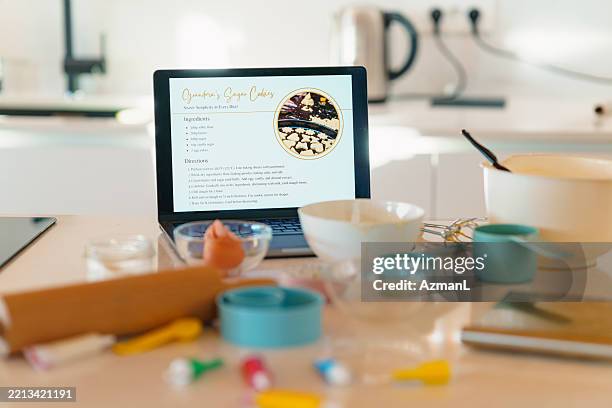 cozy domestic kitchen with baking tools and recipe laptop - cookbook stock pictures, royalty-free photos & images