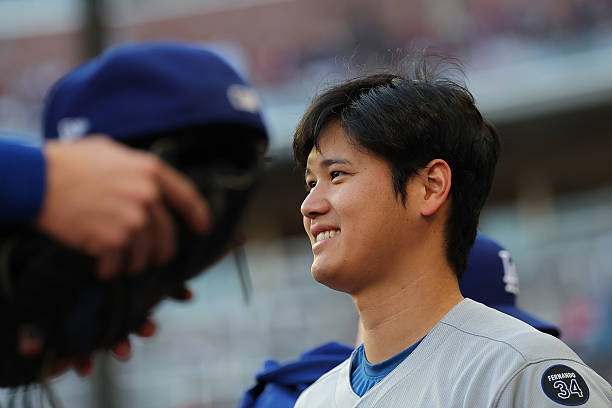 Shohei Ohtani of the Los Angeles Dodgers reacts with his teammates at the end of the second inning against the Atlanta Braves at Truist Park on May...