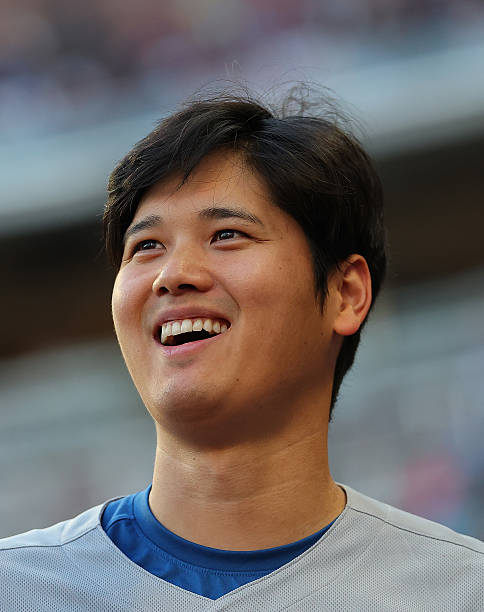 Shohei Ohtani of the Los Angeles Dodgers reacts with his teammates at the end of the second inning against the Atlanta Braves at Truist Park on May...