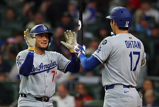 Miguel Rojas of the Los Angeles Dodgers reacts with Shohei Ohtani after hitting a solo homer in the seventh inning against the Atlanta Braves at...