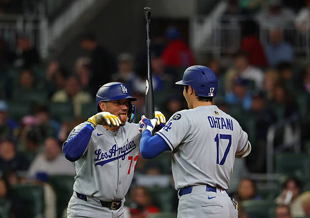 Miguel Rojas of the Los Angeles Dodgers reacts with Shohei Ohtani after hitting a solo homer in the seventh inning against the Atlanta Braves at...