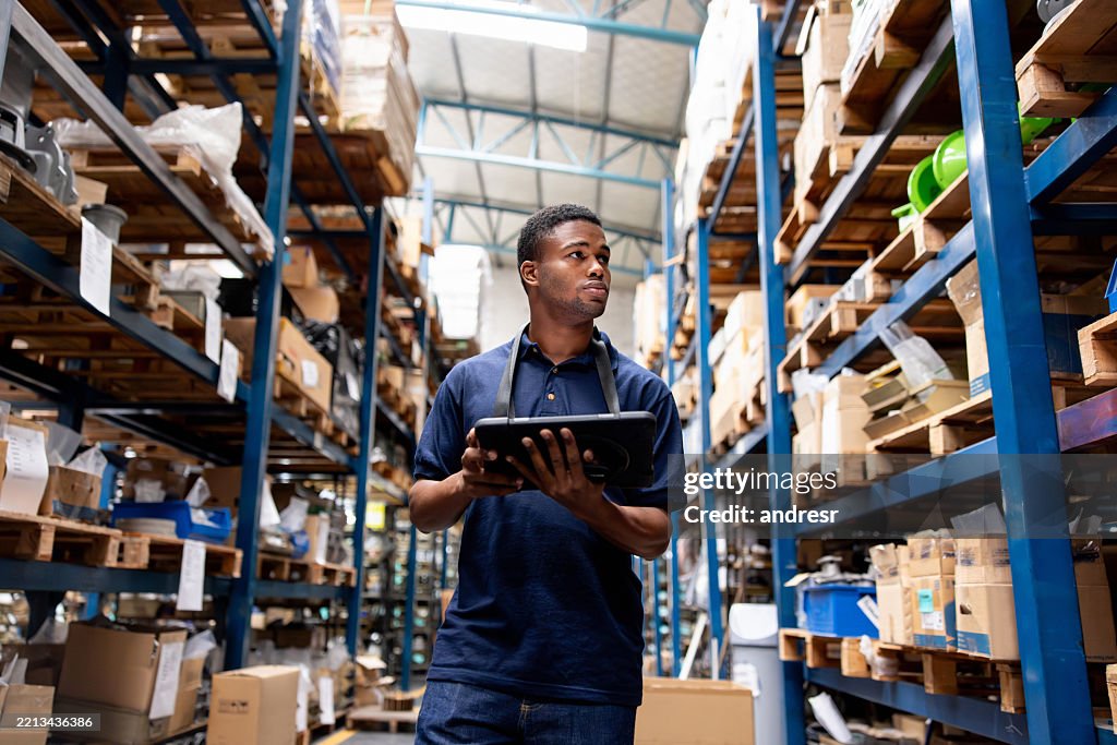 Warehouse worker taking inventory of the merchandise using a digital tablet