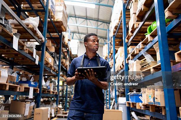 warehouse worker taking inventory of the merchandise using a digital tablet - obter inventário imagens e fotografias de stock