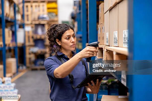 woman working at a distribution warehouse taking inventory using a bar code reader and a tablet - checklist stockfoto's en -beelden