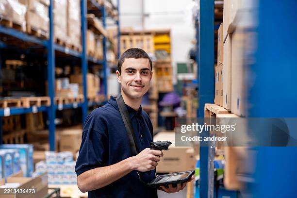 portrait of an employee taking inventory while working at a distribution warehouse - warehouse worker stock pictures, royalty-free photos & images