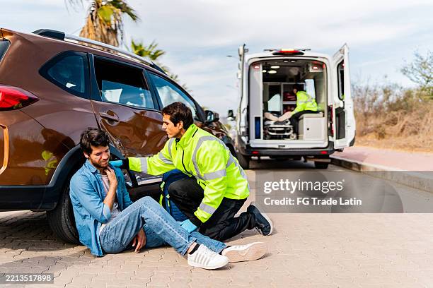 paramedic assisting injured man after car accident outdoors - acidente evento relacionado com o transporte imagens e fotografias de stock