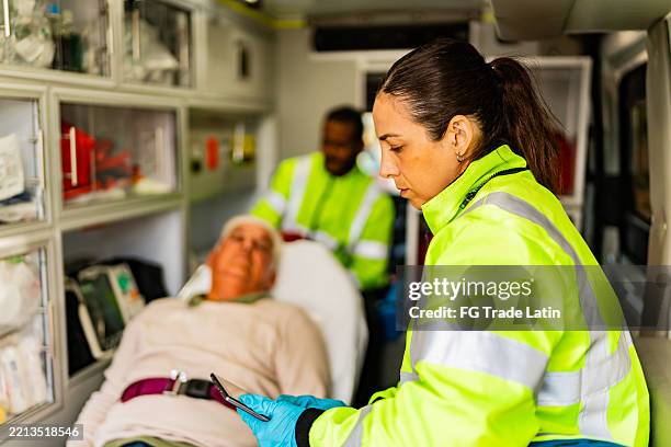 mid adult paramedic woman using tablet in ambulance - paramedic stock pictures, royalty-free photos & images