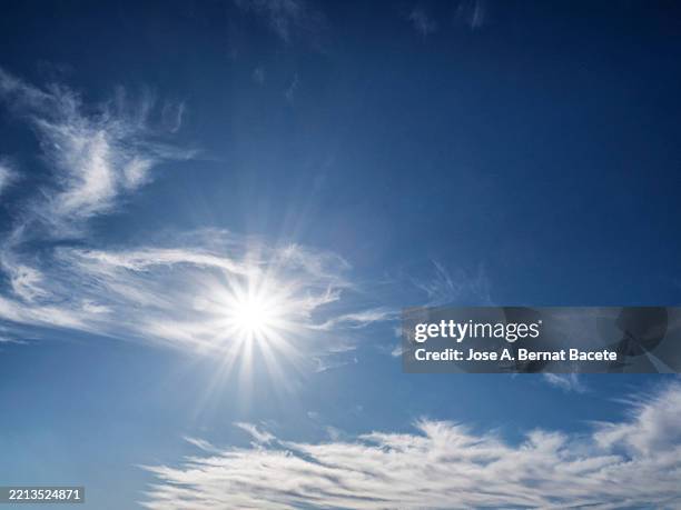 blue sky at midday with the sun shining on the horizon. - mezzogiorno foto e immagini stock