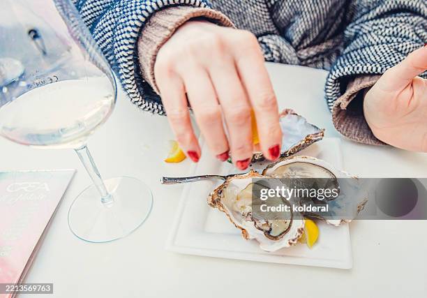 woman eating oysters in sidewalk restaurant - crustacean stock pictures, royalty-free photos & images