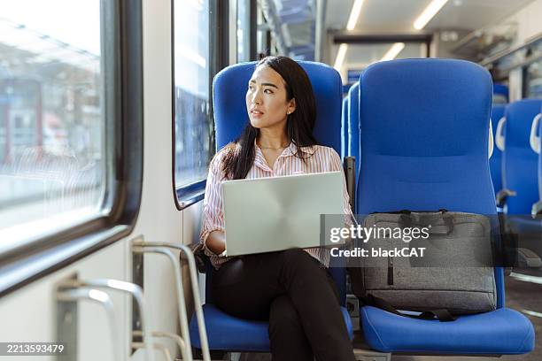 young professional working on laptop while traveling by train - east asian ethnicity stock pictures, royalty-free photos & images