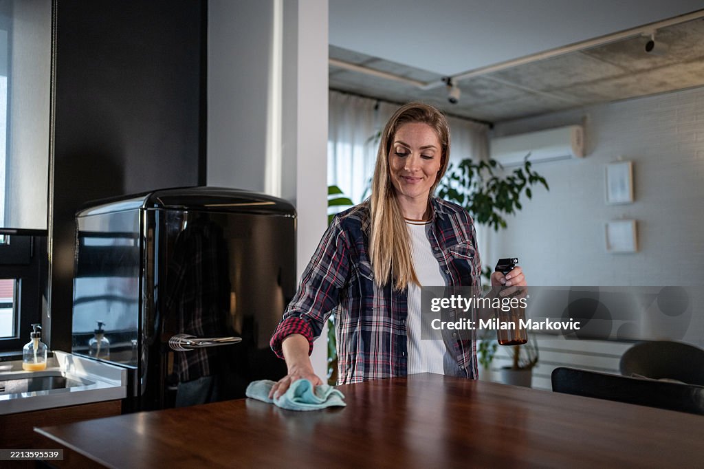 Woman cleaning kitchen counter with spray bottle
