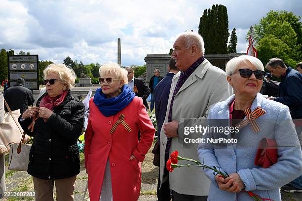 People hold flowers before a flower-laying ceremony at the Soviet military cemetery as they take part in the 80th anniversary of Victory Day and the...